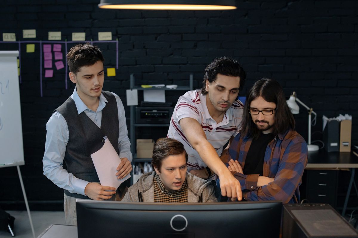 Time de desenvolvimento reunido em volta de um computador, discutindo um projeto